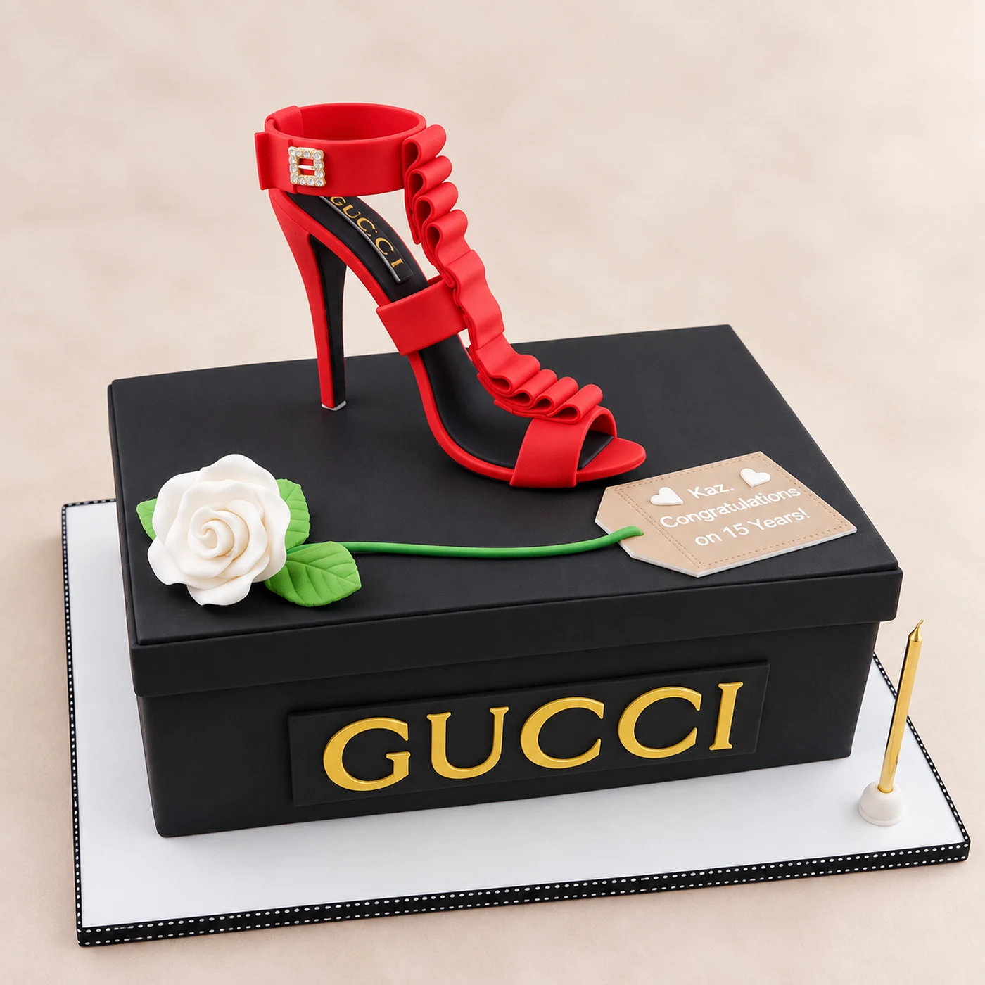 Black Gucci shoebox cake with a sculpted red high heel, white sugar rose and gold lettering